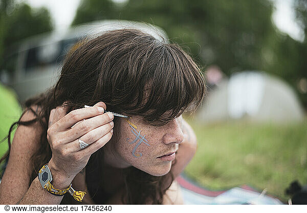 natural woman with freckles paints face at camp picnic festival