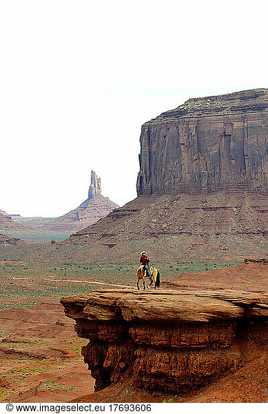 Navajo rider on rock overhang - Monument Valley Utah ; posing for tourists