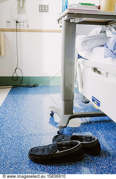 Navy blue slippers on floor in hospital room beside bed and table