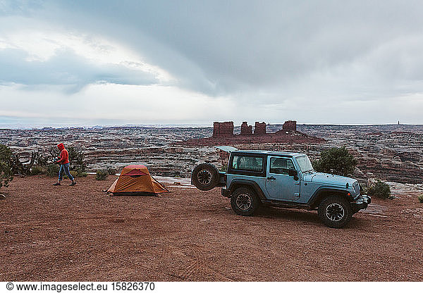 neben einem orangefarbenen Zelt geparkter Jeep an einem Regentag in Canyonlands Utah