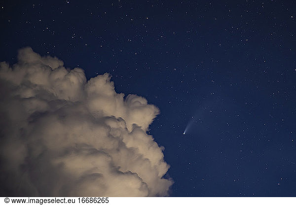 Neowise moving in the night sky with a puffy cloud