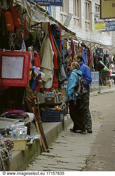 NEPAL Namche Bazaar - Wanderer stöbern in den Geschäften von Namche Bazaar. Auch wenn in Namche in den Monsunmonaten kein reges Treiben herrscht  so hat es doch seinen Charme und bietet bessere Möglichkeiten  die Einheimischen kennen zu lernen als in der Hauptsaison. Trekking in der Everest-Region in den Monsunmonaten wird für einige immer beliebter. Die Aussichten sind zwar nicht so spektakulär wie in der Hauptsaison  aber die schwer fassbaren  wolkenverhangenen Landschaften sind bezaubernd. In der Monsunzeit zeigt sich die Everest-Region von einer anderen Seite  mit leuchtenden Blumen und weniger Wanderern  was eine andere Wanderung als die übliche ermöglicht -- Bild von Jon Mitchell / Lightroom Photos.
