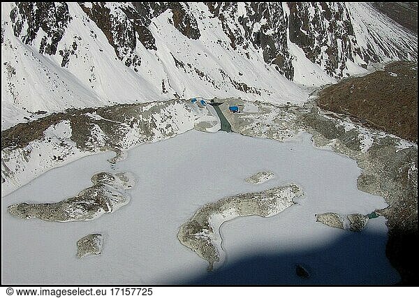NEPAL Trakarding Glacier (Lake Tsho Rolpa) -- 16 Apr 2005 -- Luftaufnahme des Tsho Rolpa - eines Gletschers am Fuße des Trakarding-Gletschers  der bemerkenswert ist  da er eines von 13 bekannten Gebieten ist  in denen die Gefahr eines Gletscherüberlaufs besteht - wenn sich das von der Gletscherschmelze stammende Wasser in einem natürlichen See  wie dem hier abgebildeten Tsho Rolpa (Chhyugima Pokhari)  staut (Bildmitte). Bei den kleinen blauen Gebäuden in der Mitte des Bildes handelt es sich um eine von den Niederlanden gebaute Pumpstation  die das Risiko eines Überlaufs mindert. Dieser Fall von Gletscherüberbruch bedroht viele Kilometer Flusstäler  vor allem entlang des Rolwaling-Flusses - hier im Bild - und des Tamakhosi-Flusses weiter westlich usw. Wissenschaftler haben davor gewarnt  dass die steigenden Temperaturen infolge der globalen Erwärmung den Untergang dieser Eisfälle und Gletscher im Himalaya verursachen könnten. Die Auswirkungen werden wahrscheinlich viele asiatische Länder betreffen  da diese Gletscher - und die Gletscher im benachbarten Tibet - die meisten der großen Flusssysteme von Pakistan bis China speisen. Weitreichende Überschwemmungen haben begonnen und werden voraussichtlich anhalten. Während des Monsuns 2004 waren etwa 30 Millionen Menschen in Nepal  Indien und Bangladesch von schweren Überschwemmungen betroffen. Wissenschaftler fügen hinzu  dass nach dem Abschmelzen der Gletscher ihr Rückzug zu einer weit verbreiteten Dürre in vielen Gebieten Asiens führen wird -- Bild ? Jon Mitchell / Lightroom-Fotos.