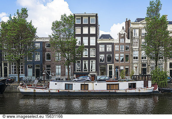 Netherlands  Amsterdam  Barge moored along edge of city canal with row of houses in background