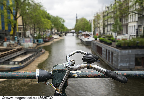 Netherlands  Amsterdam  Handlebar of bicycle parked along railing of canal bridge