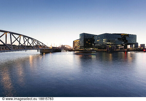 Netherlands  North Holland  Amsterdam  Bridge over city canal at dusk with modern buildings in background