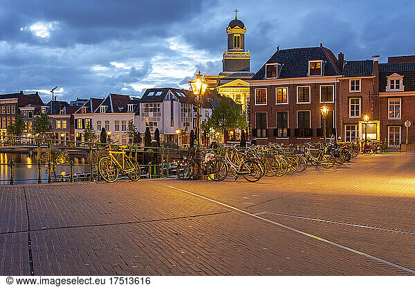 Netherlands  South Holland  Leiden  Bicycles parked along illuminated old town street at dusk