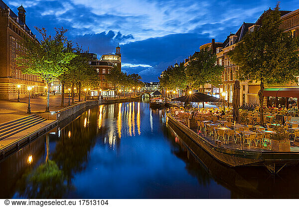 Netherlands  South Holland  Leiden  Sidewalk cafe and illuminated Nieuwe Rijn canal at dusk