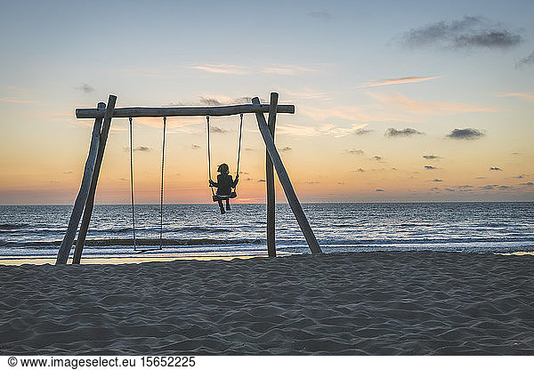 Netherlands  South Holland  Noordwijk  child on beach swing at sunset