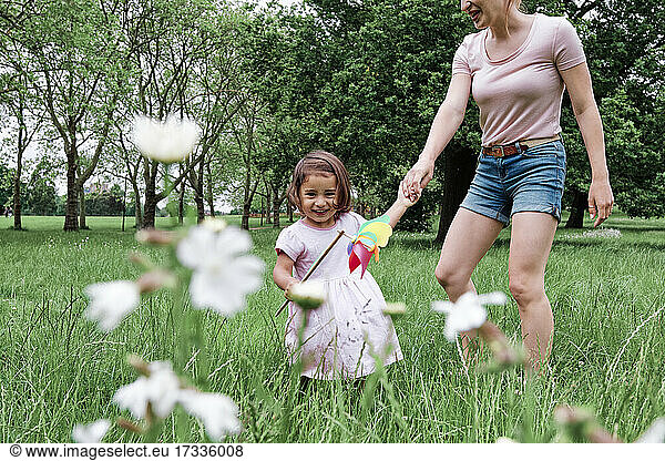 Nettes Mädchen hält Windrad mit Mutter im Park