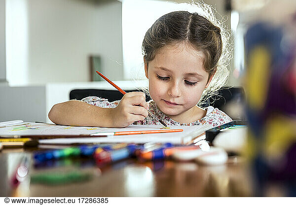 Nettes Mädchen malt mit Pinsel auf Papier zu Hause