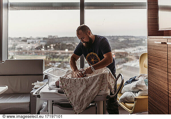 Neugeborener Vater wechselt die Windel seines neugeborenen Jungen im Krankenhaus nach der Geburt