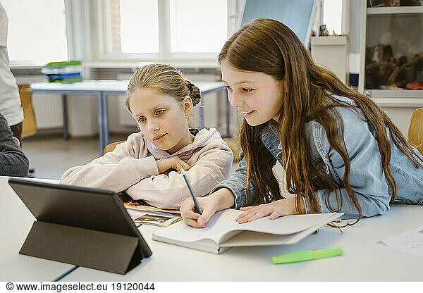 Neugierige Schülerinnen beim E-Learning über einen Tablet-PC am Schreibtisch im Klassenzimmer