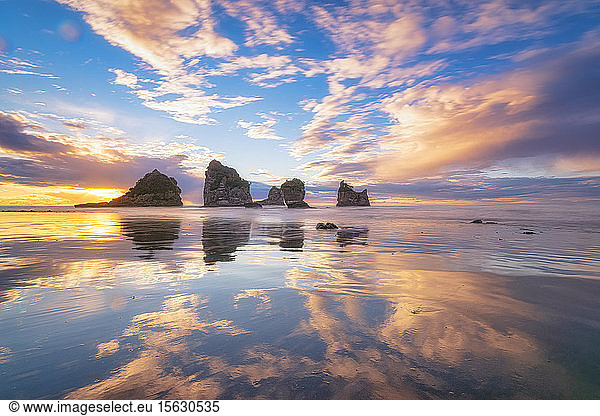 Neuseeland  Südinsel  Wolken und Meeresschornsteine spiegeln sich im glänzenden Küstenwasser des Motukiekie Beach bei Sonnenuntergang