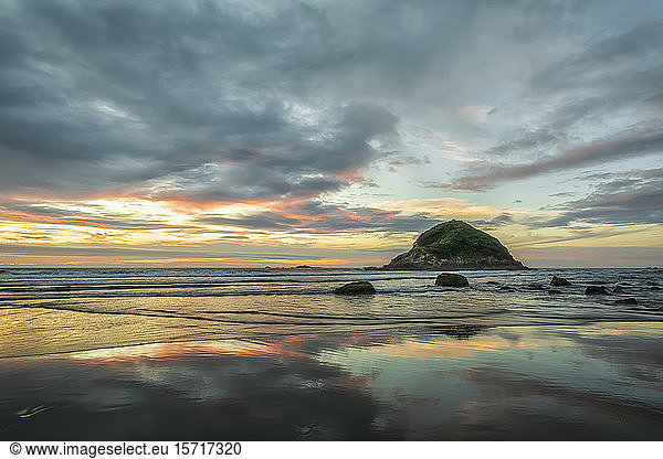 Neuseeland Tongaporutu Bewölkter Himmel über dem Sandstrand in der Abenddämmerung mit der Insel Motuotamatea im Hintergrund