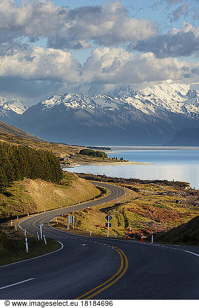 New Zealand  Canterbury Region  Winding asphalt road with Lake Pukaki and Mount Cook in background