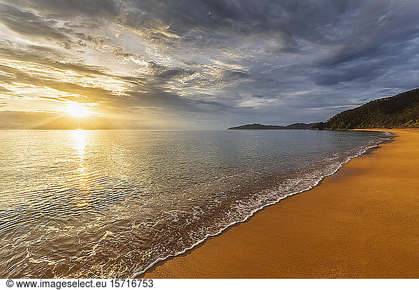 New Zealand  Clouds over sandy coastal beach at sunset