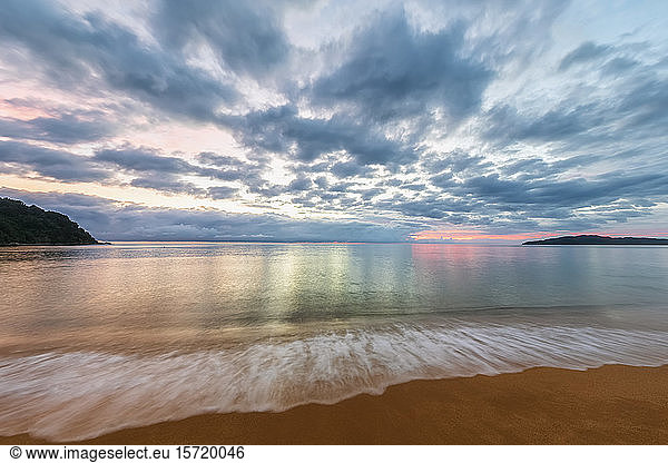 New Zealand  Long exposure of clouds over sandy coastal beach at dusk