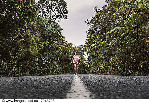 New Zealand  North Island  Northland  Young man running on road through Waipoua Forest