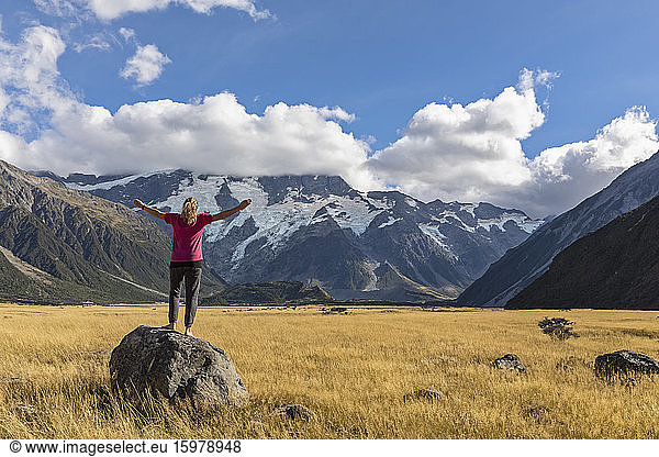 New Zealand  Oceania  South Island  Canterbury  Ben Ohau  Southern Alps (New Zealand Alps)  Mount Cook National Park  Aoraki / Mount Cook  Woman standing on boulder in mountain landscape