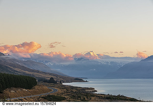 New Zealand  Scenic view of New Zealand State Highway 80 stretching along shore of Lake Pukaki at dawn with Mount Cook in background