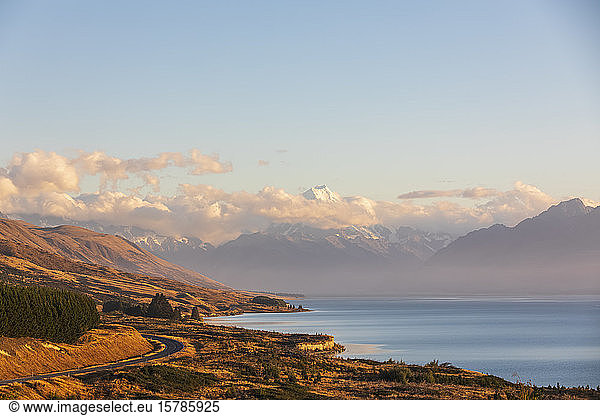 New Zealand  Scenic view of New Zealand State Highway 80 stretching along shore of Lake Pukaki at dawn with Mount Cook in background