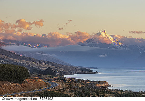 New Zealand  Scenic view of New Zealand State Highway 80 stretching along shore of Lake Pukaki at dawn with Mount Cook in background