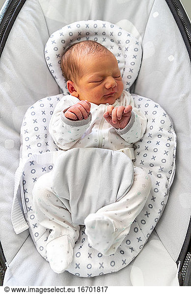 Newborn baby sleeping with his fingers raised.