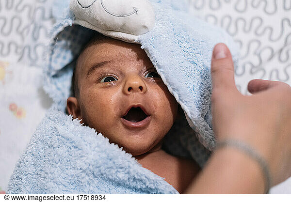 Newborn baby wrapped in a bath towel. Screaming happily.