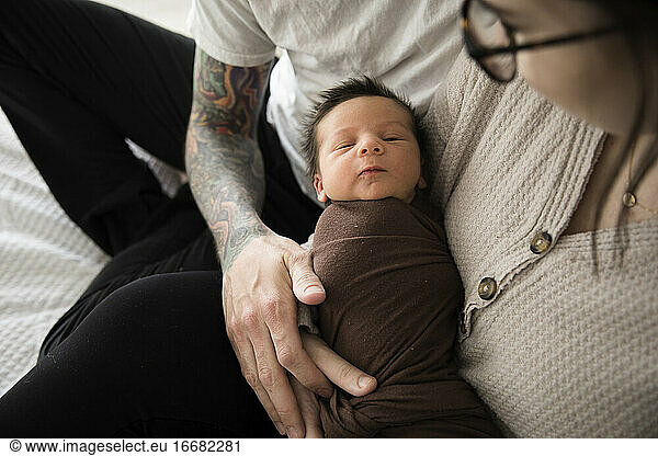 Newborn Boy Swaddled in Brown  Held By Tattooed Hipster Parents