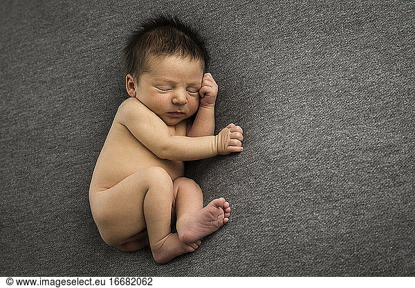 Newborn Boy With Lots of Hair Sleeps on Gray Background