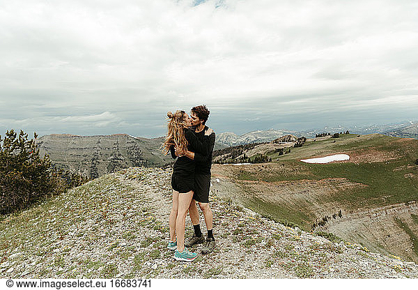 newly engaged white couple kiss on a mountain top in wyoming