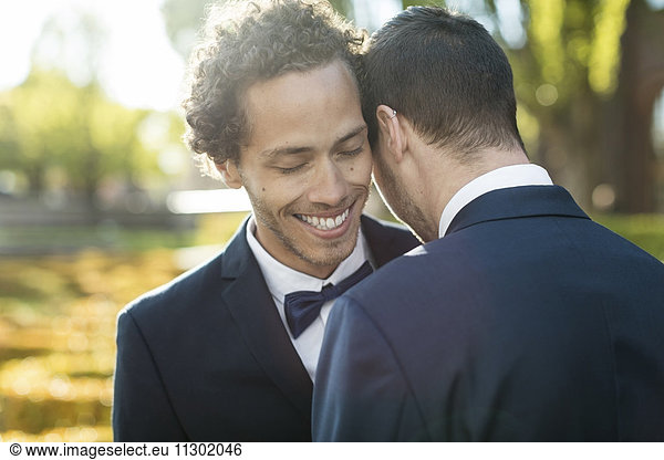 Newlywed gay couple embracing outdoors