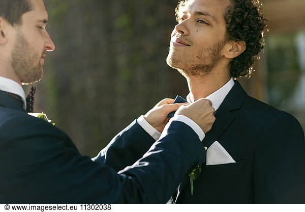Newlywed man adjusting bow tie of gay partner