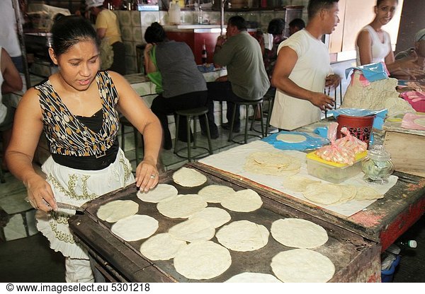 Nicaragua  Managua  Mercado Roberto Huembes  market  shopping  food vendor  flour  tortilla  flatbread  Hispanic  woman  man  cook  hot griddle  traditional food  staple  cafeteria  customer  restaurant  preparing