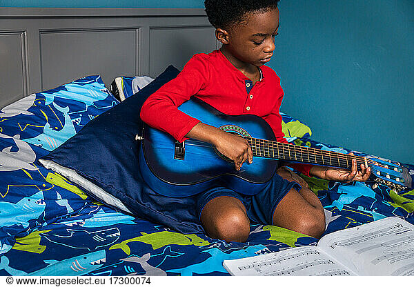 Niedlicher Junge lernt Gitarre zu Hause