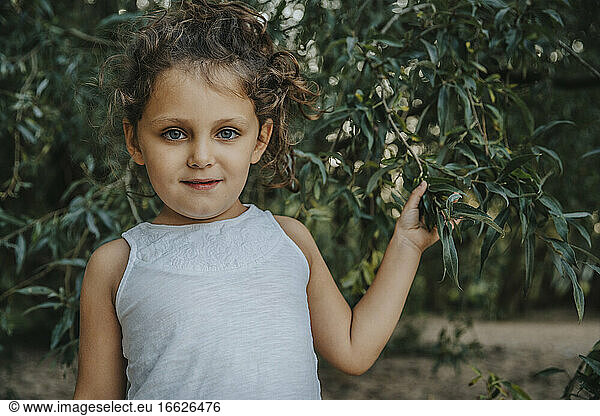 Niedliches kleines Mädchen unter Weidenbaum stehend