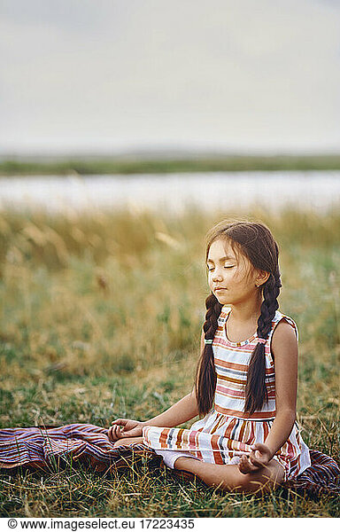 Niedliches Mädchen meditiert im Gras