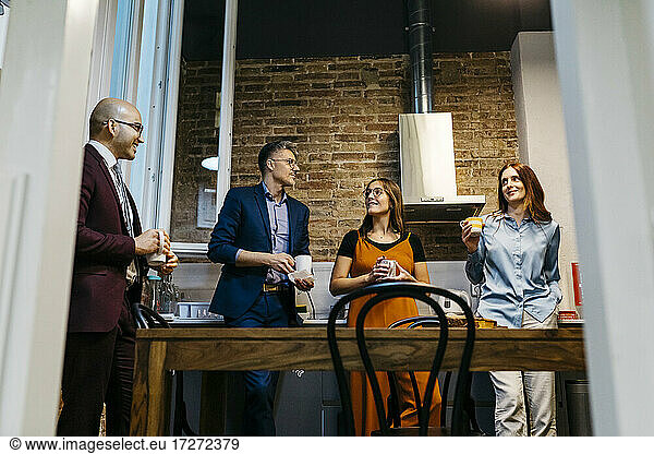 Niedriger Blickwinkel von männlichen und weiblichen Unternehmern  die sich bei einem Kaffee in der Büroküche unterhalten