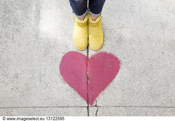 Niedriger Querschnitt einer Person  die auf dem Fußweg an der Form eines roten Herzens steht