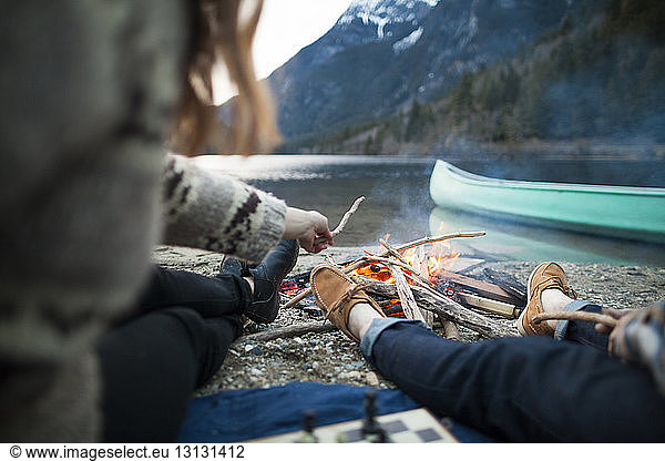 Niedriger Teil des Paares sitzt am brennenden Lagerfeuer im Silver Lake Provincial Park