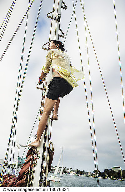 Niedrigwinkelansicht eines Mannes  der am Mast eines Segelbootes klettert