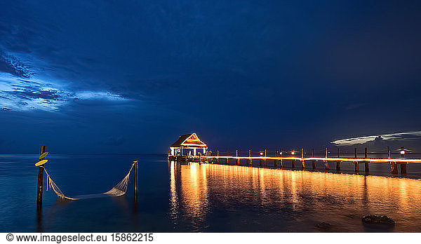 Night pier view on the sea illuminated with hammock on the water