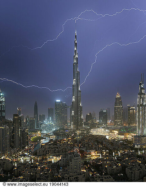 Night view of Dubai skyline with lightning striking Burj Khalifa