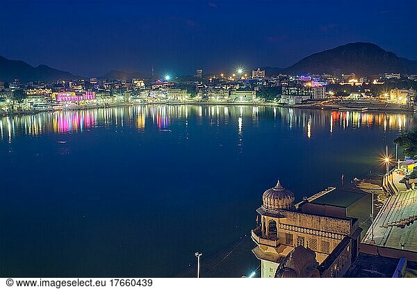 Night view of famous indian hinduism pilgrimage town sacred holy hindu religious city Pushkar with Brahma temple  aarti ceremony  lake and ghats illuminated. Rajasthan  India. Horizontal pan