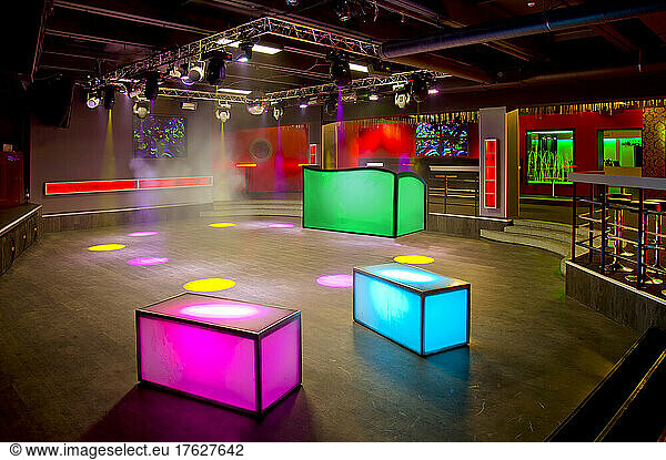 Nightclub interior  colourful lighting  wall screens and light boxes on a dance floor.