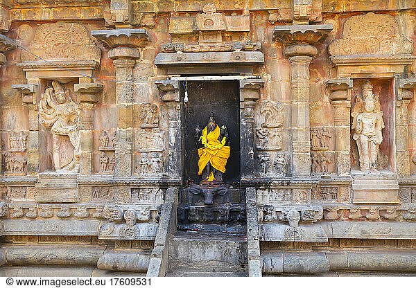 Nische mit einer in leuchtend gelbe Seide gehüllten Statue einer Hindu-Gottheit in einer Steinwand des Airavatesvara-Tempels aus der dravidischen Chola-Zeit; Darasuram  Tamil Nadu  Indien