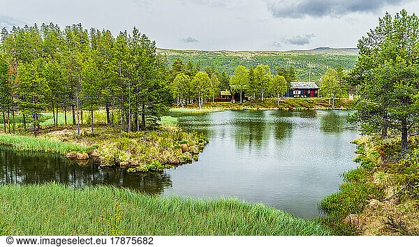 Norway  Innlandet  Lake in Rondane National Park with secluded hut in background