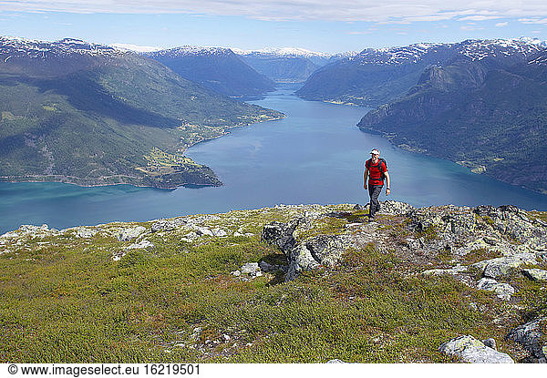 Norway  Lustrafjord  Man hiking across cliff line