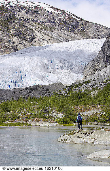 Norway  Nigardsbreen  Glacier tongue  Hiker on shore  rear view